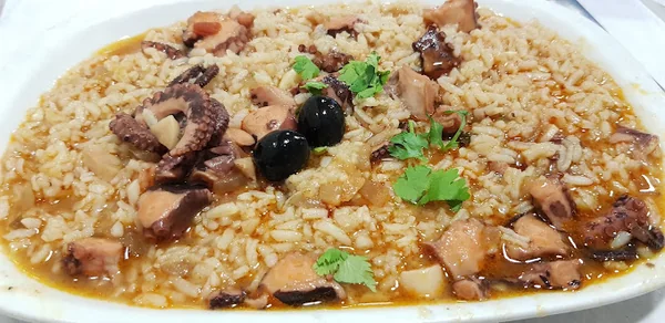 Arroz de polvo num prato oval, com azeitonas e coentros